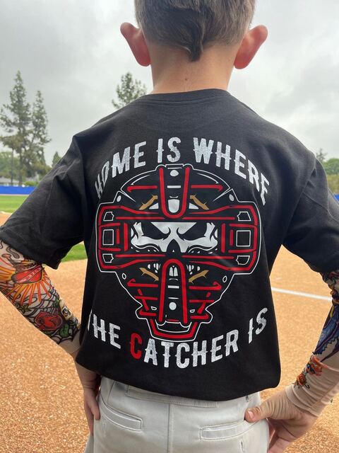 Back of the black Home Is Where The Catcher Is tee on a young player
